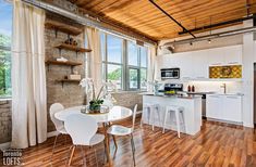 an open kitchen and dining area with wood flooring, white cabinets, and wooden ceiling