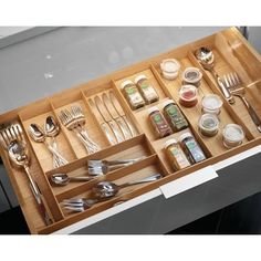 an open drawer with utensils and spoons in it on top of a table