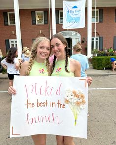 two girls holding up a sign that says pick the best in the bunch and flowers