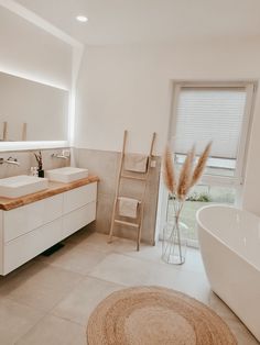 a bathroom with a large white tub next to a walk in shower and two sinks