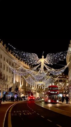 a city street is decorated with christmas lights and angel decorations, as people walk on the sidewalk