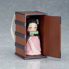 a figurine in a wooden box with a green ribbon around it's neck