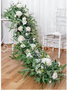 white flowers and greenery are arranged on the floor