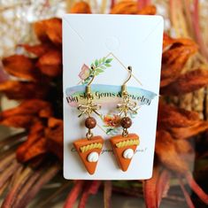 the earrings are on display in front of a flowery background with an orange and white design