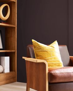 a brown leather chair sitting in front of a wooden book shelf with books on it