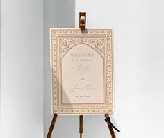 an easel with a welcome sign on it sitting in front of a white wall