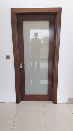 a man standing in front of a glass door with the reflection of him on it