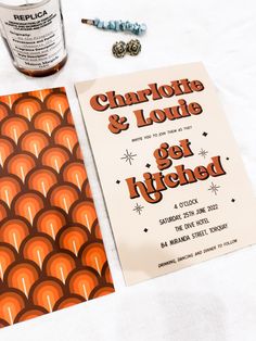 an orange and brown poster next to a bottle of liquor on a white tablecloth