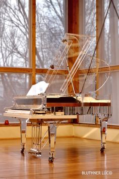 a grand piano sitting on top of a hard wood floor in front of a window