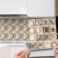 two hands are holding an object in front of a kitchen counter with tiles on it