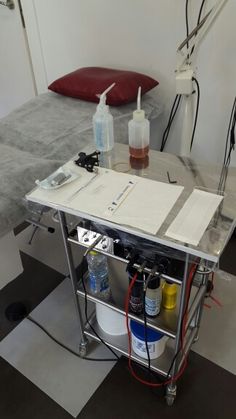 a table that has some bottles on top of it in front of a bed with a red pillow