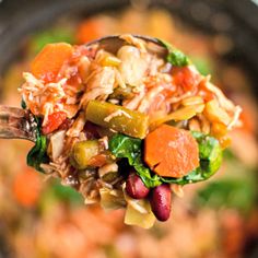 a spoon full of rice and vegetables being held up