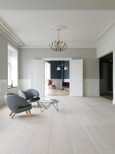 an empty living room with two chairs and a coffee table on the floor in front of it