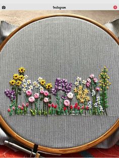 a close up of a embroidery on a hoop with flowers in the middle and behind it