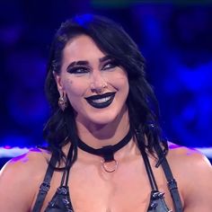 a woman with black makeup and piercings on her face is smiling at the camera