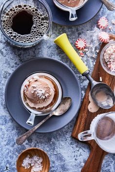 hot chocolate and marshmallows are served in mugs with spoons on the side