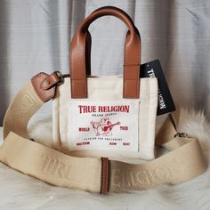 -Super Cute Mini Cream Canvas Tote With "True Religion Logo On Front Pocket -Comes With Adjustable/Detachable Crossbody Strap And Two Handbag Handles -Bag Can Be Worn As A Crossbody Bag Or Handbag -Has Magnetic Snap Closure -New With Tags. No Damages Dimensions: W:7½" H:6½" D:4" True Religion Purse, Everyday Bags With Logo Strap And Double Handle, Rectangular Canvas Bag With Branded Hardware, Rectangular Canvas Bags With Branded Hardware, Rectangular Canvas Shoulder Bag With Branded Hardware, Daily Use Canvas Shoulder Bag With Branded Hardware, Canvas Bags With Branded Hardware For Everyday Use, Daily Use Tote Bag With Logo Strap, Everyday Logo Strap Tote Shoulder Bag