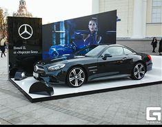 a mercedes car on display in front of a large advertisement for its new showroom