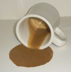 a coffee cup filled with caramel sauce sitting on top of a white counter