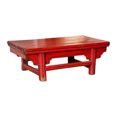 an old red wooden table sitting on top of a white floor with no one around it