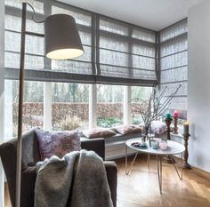 a living room filled with furniture and a large window covered in shades on the windowsill