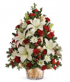 a christmas tree arrangement with white lilies and red carnations in a glass vase