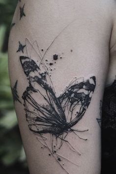 a black and white butterfly tattoo on the left upper half of the arm, with stars around it