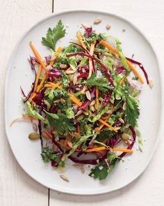 a white plate topped with lettuce, carrots and other veggies