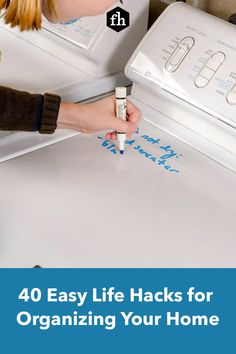 a woman is painting the back of a white refrigerator with blue writing on it and she has