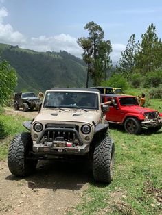 jeeps and trucks parked on the side of a dirt road