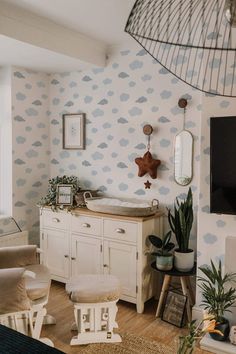 a white dresser sitting next to a tv on top of a wooden table in a living room