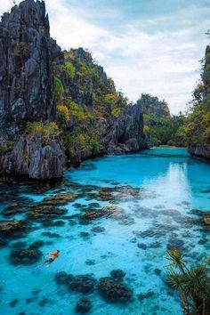 a person in a kayak is floating on the water near some rocks and trees