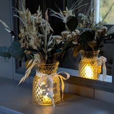 two vases filled with flowers sitting on top of a window sill