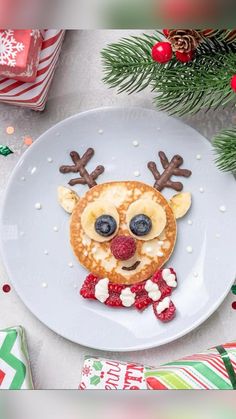 a plate topped with pancakes covered in frosting and reindeer face decorations next to christmas presents