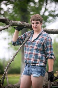 a young man standing next to a tree branch