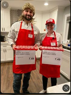 two people wearing red aprons and hats holding up signs in front of the camera