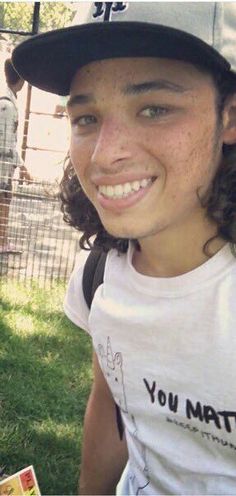 a young boy wearing a baseball cap and smiling at the camera