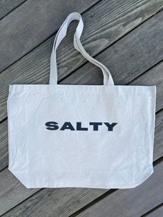 Stay salty no matter the season with the Salty Tote Bag! This extra large bag is perfect for carrying all the essentials — and then some. Bring it to the beach, farmer's market, campus, or run errands. This one can do it all and bring you beach style no matter where you go. Measures 20"W x 15"H x 5"D Casual Cotton Beach Bags, Everyday Cotton Shoulder Bag For Beach, Beachy Tote Canvas Bag For Everyday Use, Summer Bags, Recyclable For Everyday Use, Large Summer Beach Bag, Large Everyday Beach Bag For Summer, Everyday Canvas Beach Bag For Beach Season, Casual Recyclable Beach Bag, Everyday Canvas Beach Bag