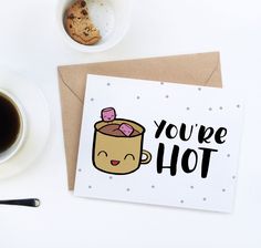 a cup of coffee next to a card that says you're hot