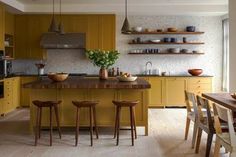 a kitchen with yellow cabinets and wooden stools