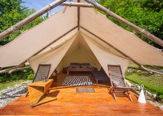 the inside of a tent with two chairs and a bed in it on top of a wooden platform