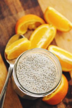 oranges and a spoon on a cutting board with a smoothie in the middle