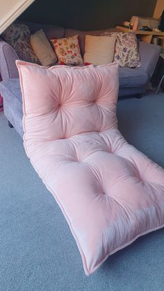 a pink futon couch sitting on top of a blue carpet