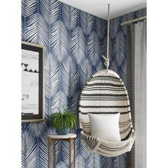 a hanging chair in the corner of a room with blue and white patterned wallpaper