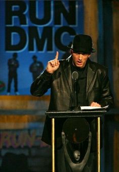 a man standing at a podium with his hand up in the air while giving a speech