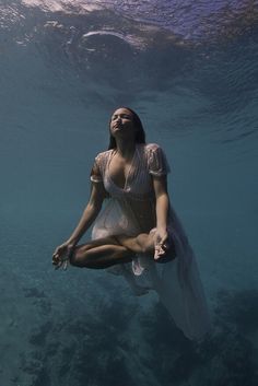 a woman in a white dress is floating under water