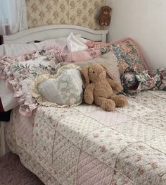 a teddy bear sitting on top of a bed next to pillows and pillowcases