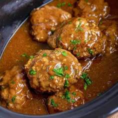 three meatballs covered in gravy and garnished with parsley in a slow cooker