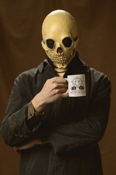 a man in a skeleton mask holding a coffee mug