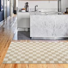 a kitchen with an island, stove and sink in the middle of it on a hard wood floor